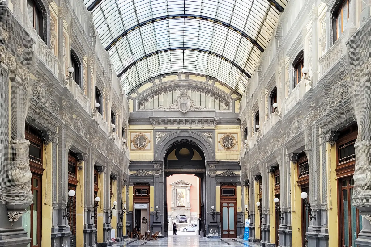 The glass-and-iron roof and painted facades inside the Galleria Principe di Napoli